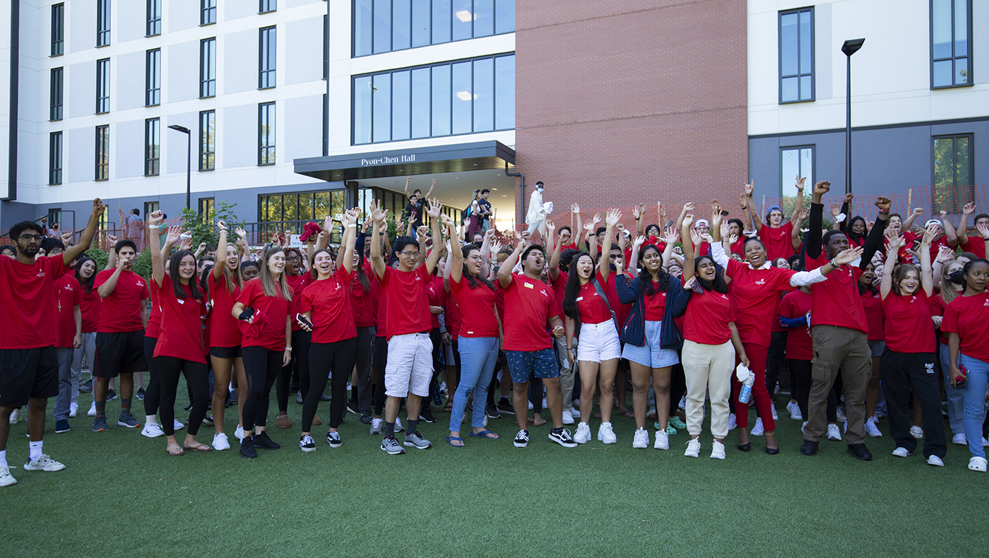 large group of students cheering in front of Pyon-Chen Hall during dedication ceremony