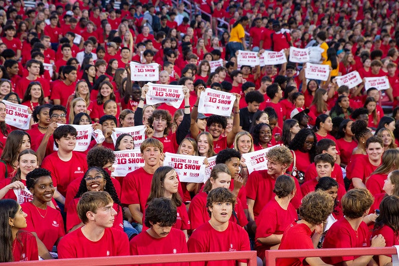 large group of students wearing red shirts and holding up rally towels in the bleachers of SECU Stadium for Fall Welcome.