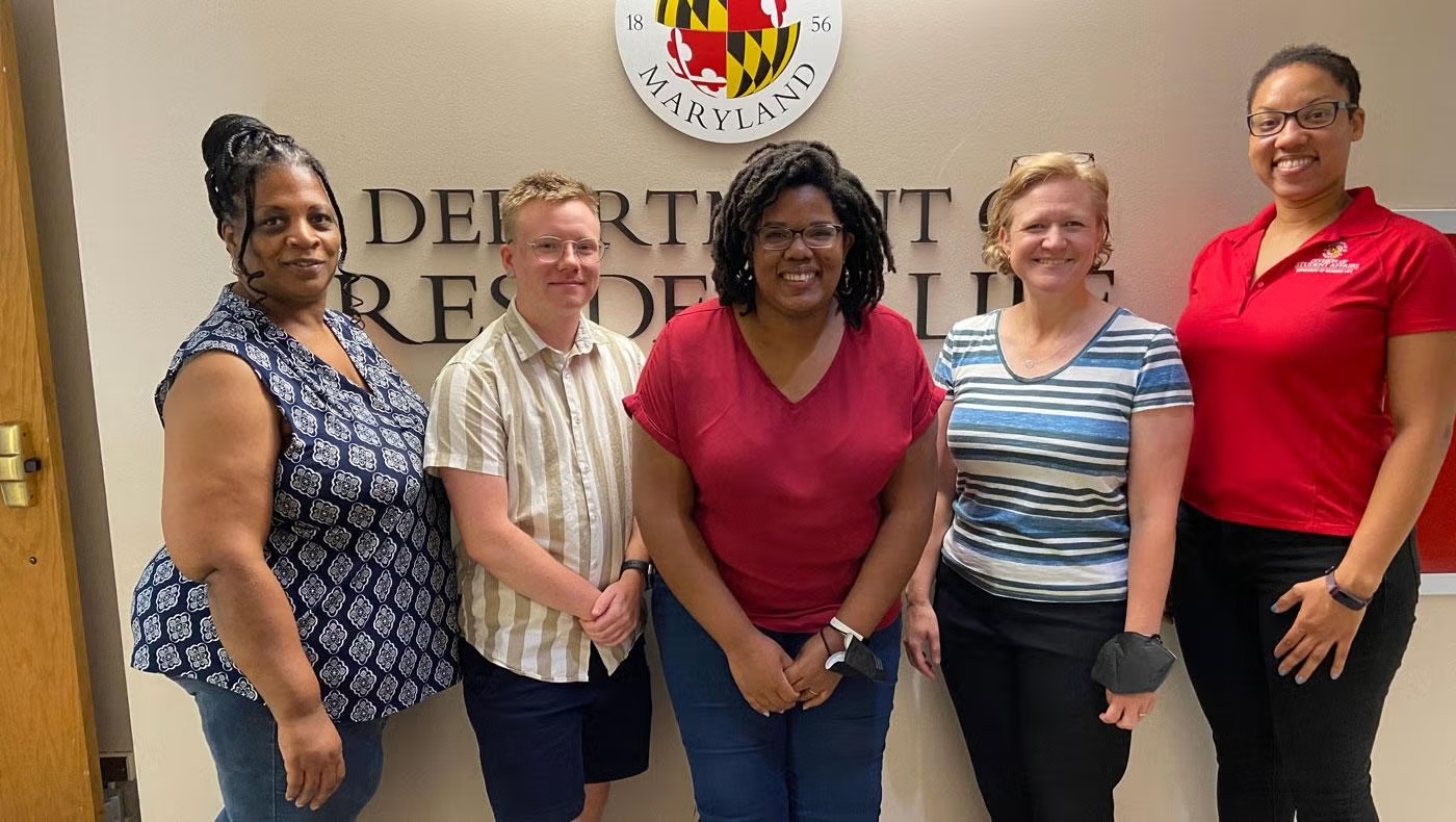 res life staff in front of department logo on wall