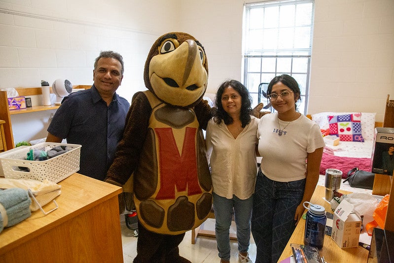 Testudo mascot with a student and her parents inside a residence hall room during move-in.