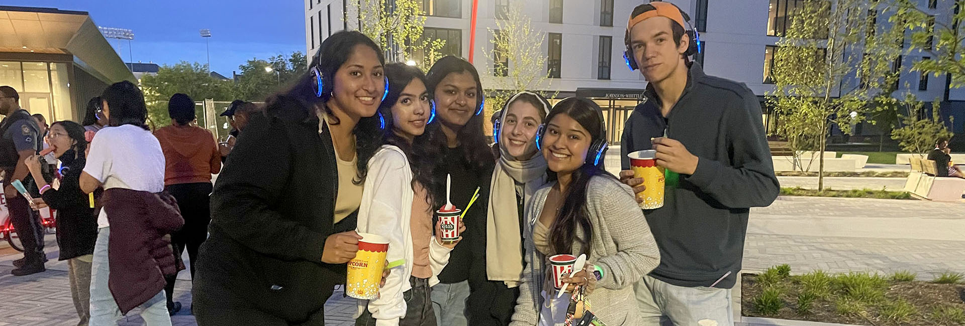 students wearing glow in the dark headphones and holding popcorn buckets