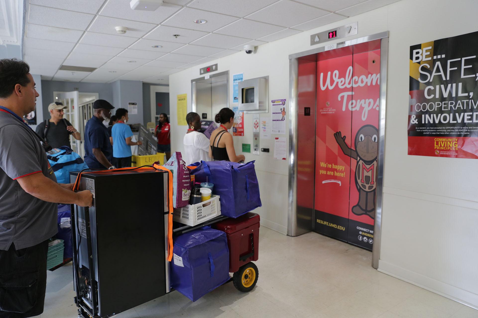 students waiting with personal belongings for elevator during move-in day