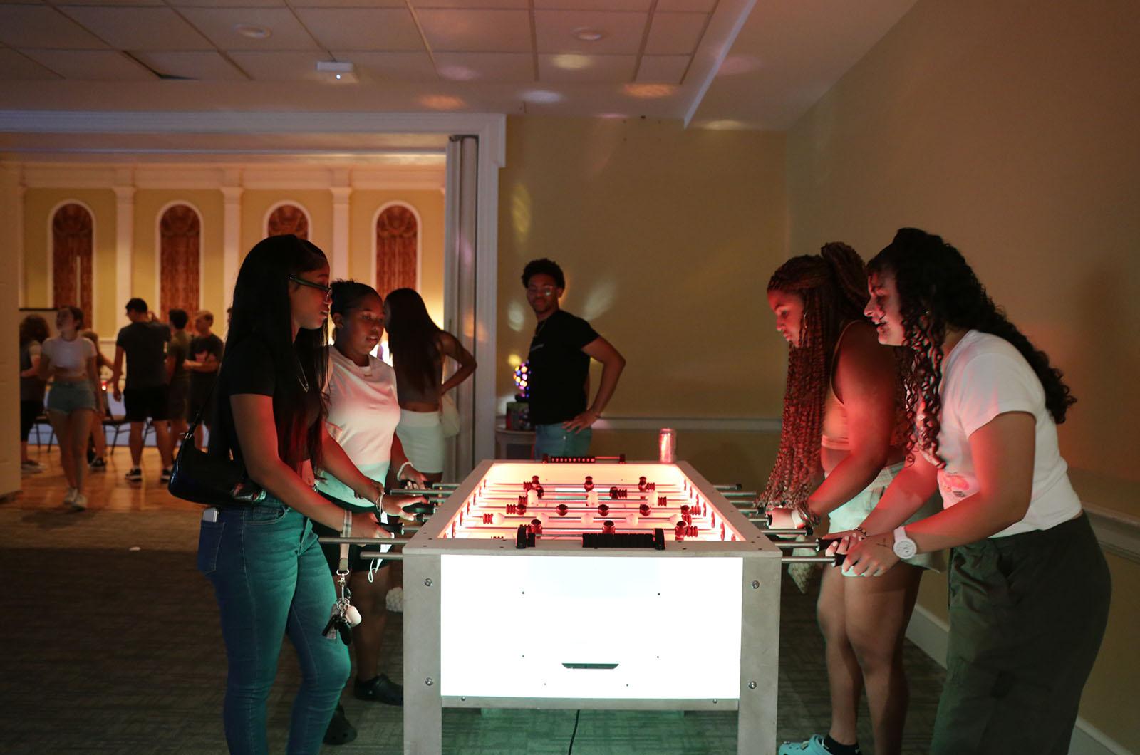 group of students playing foosball on a glowing table