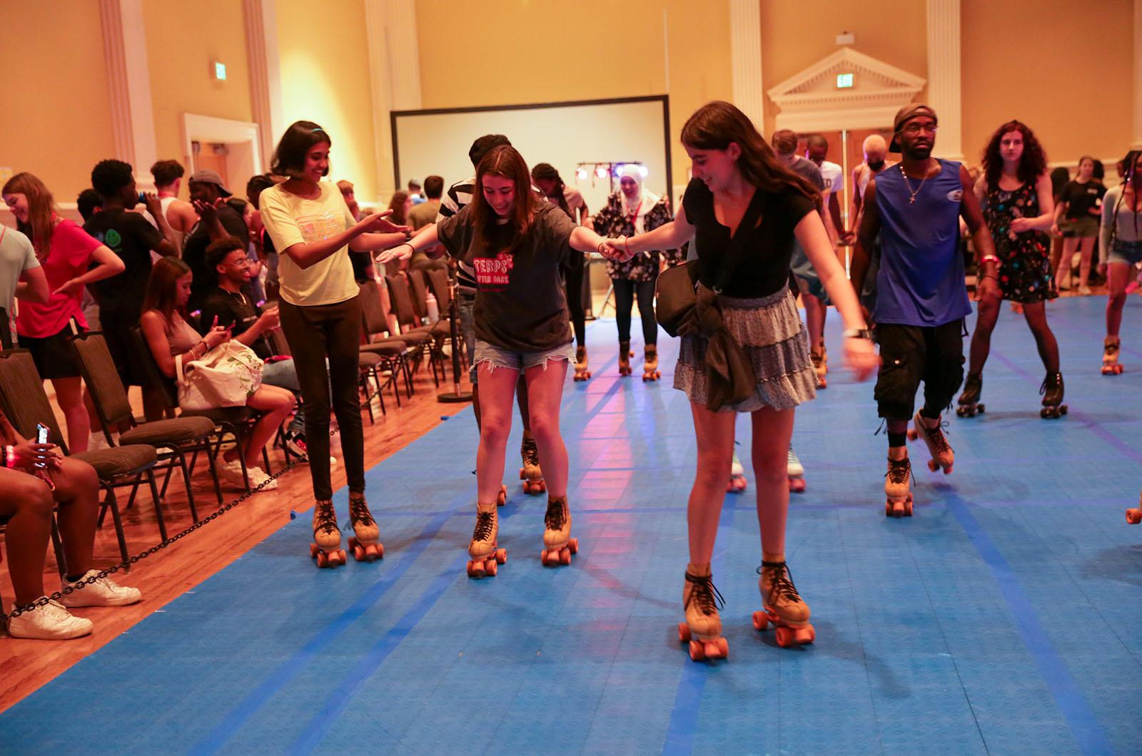 Three students roller skating together in an indoor rink during a busy night