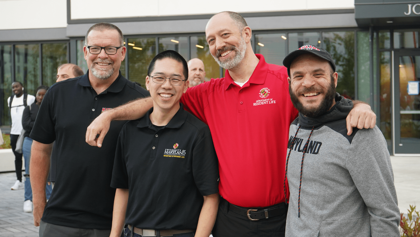 four res life staff members in front of a residence hall