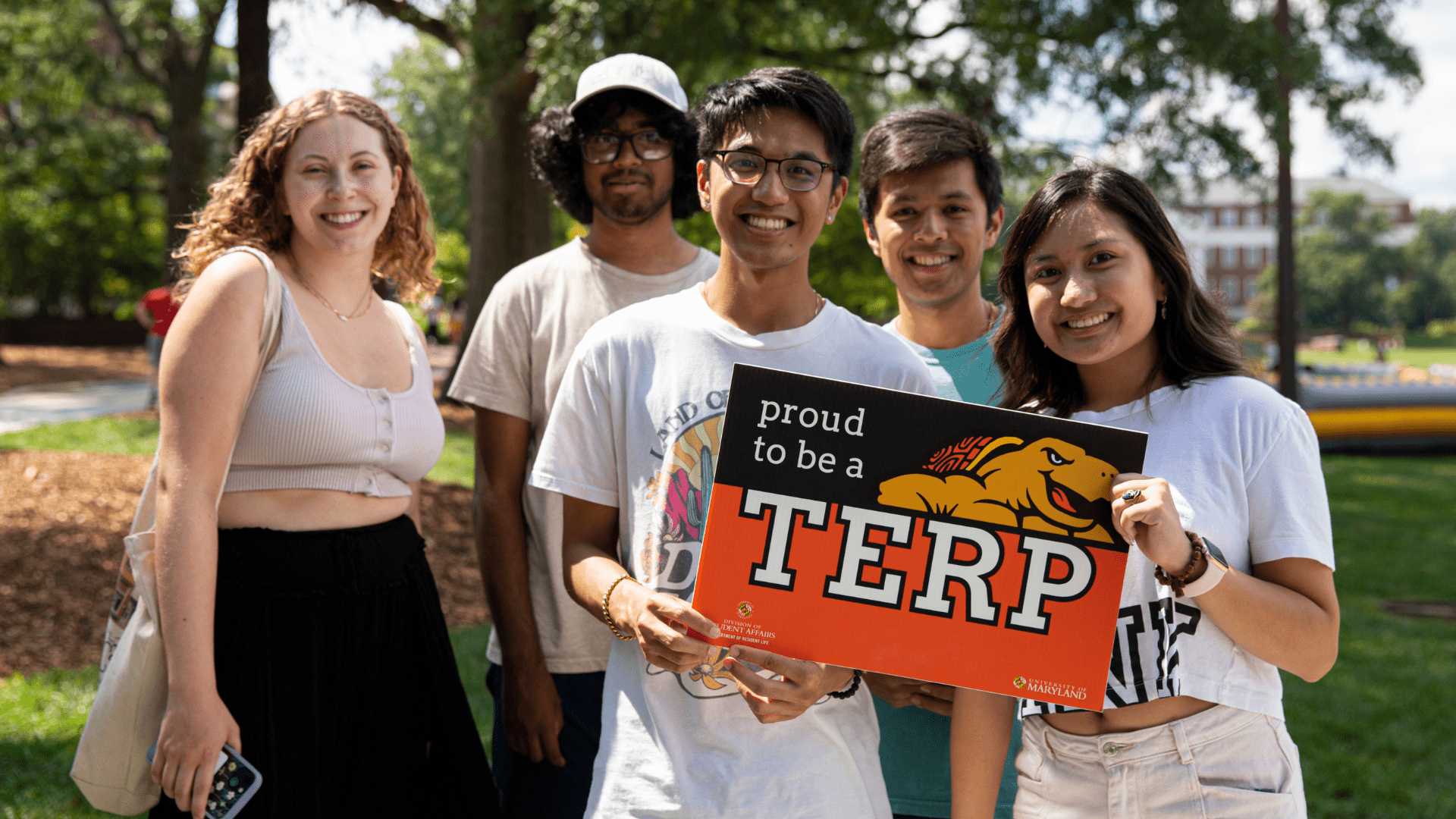 group of five students holding proud terp sign outdoors during freefest