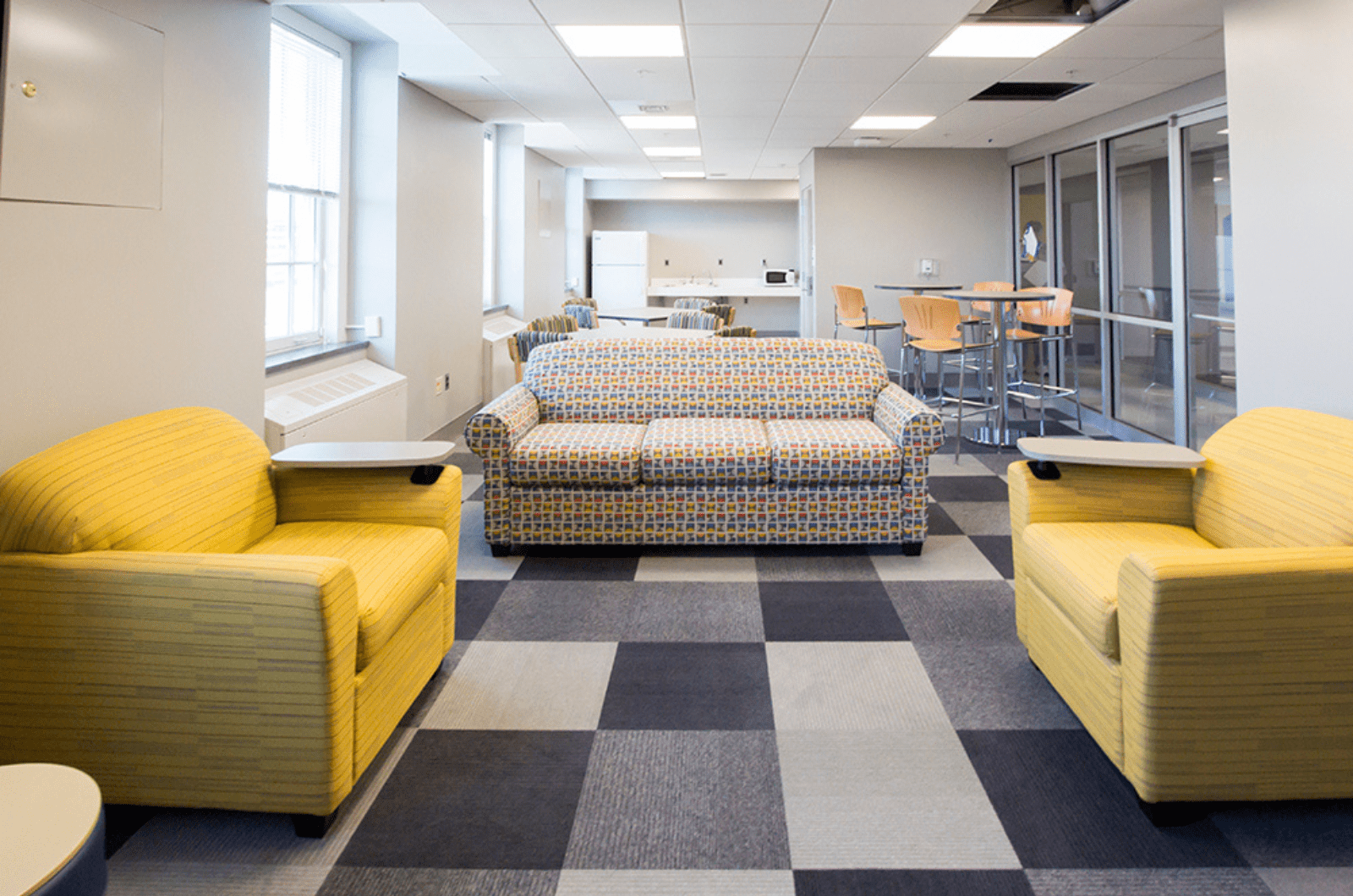 study lounge with sofa and chairs in the foreground and a kitchen with seating in the background