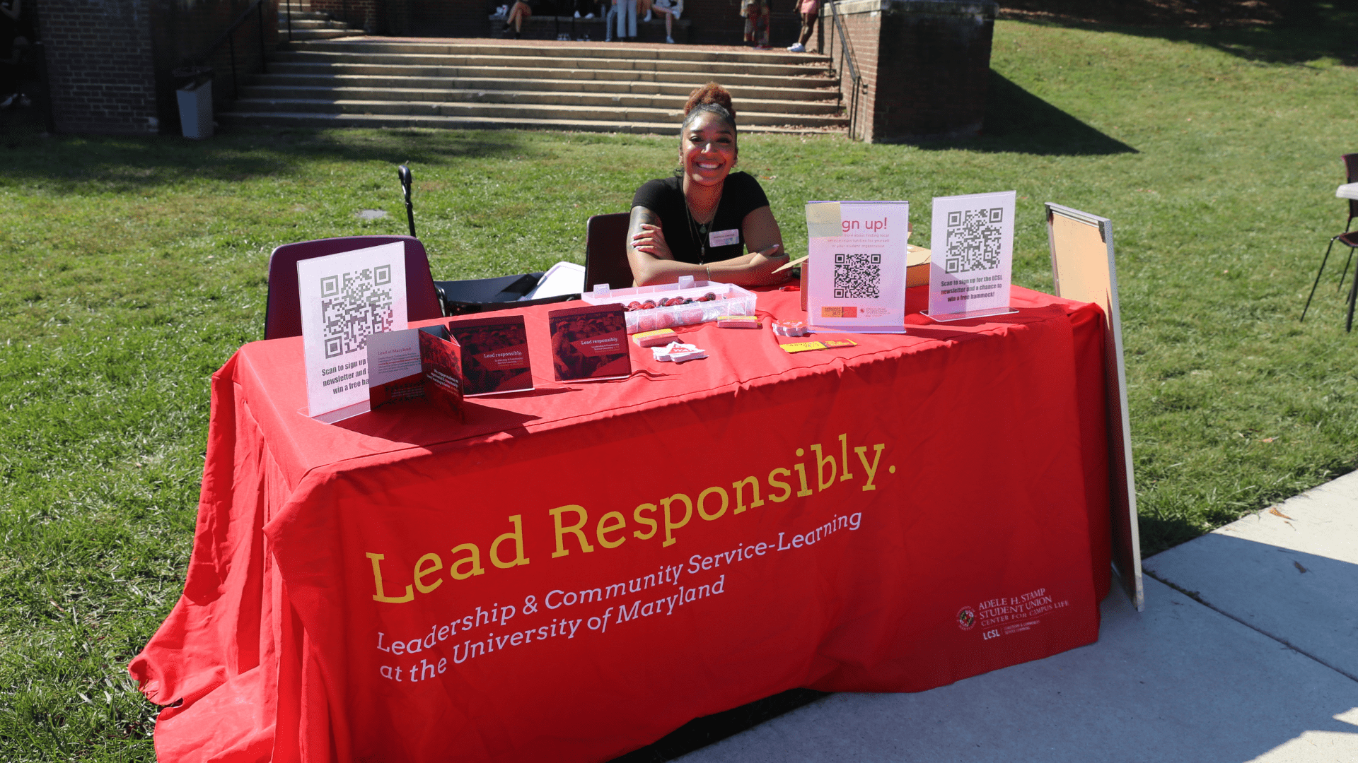 student behind a booth during an outdoor fair