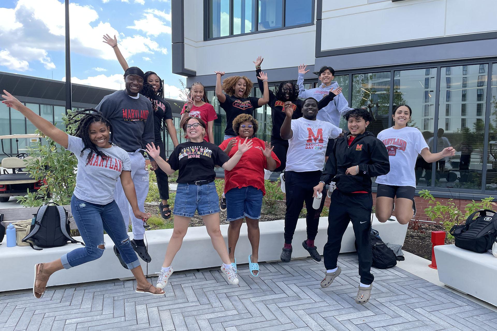 students with their resident director jumping in the air outside