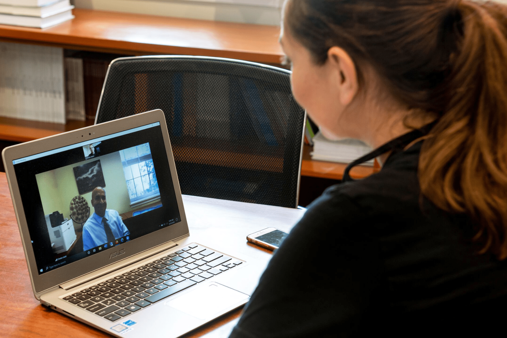 over the shoulder of a student talking to person over Zoom during a counseling session