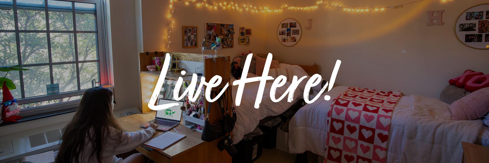 student in studying at desk near the window in residence hall room with words Live Here