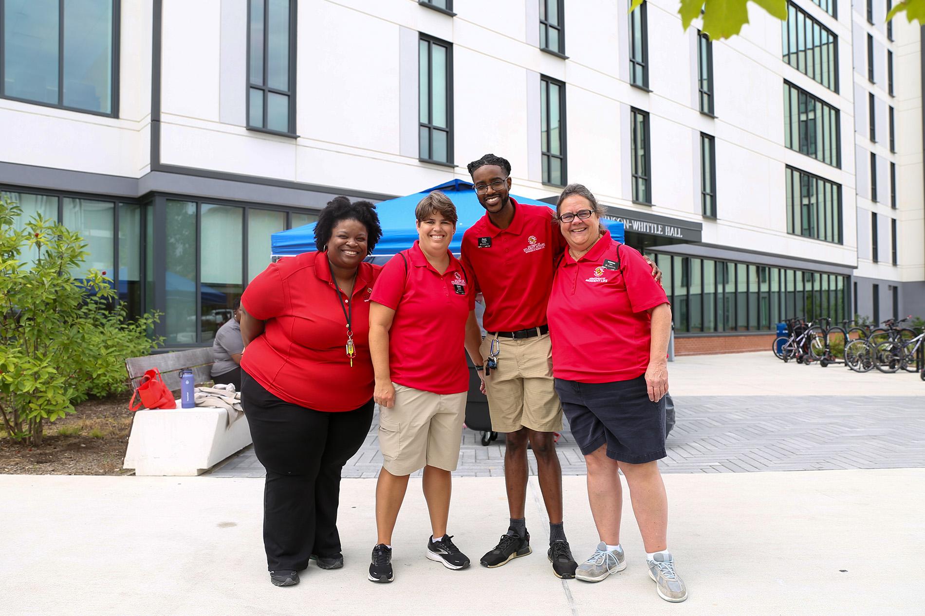 four res life staff members in red shirts in Heritage Plaza during move-in