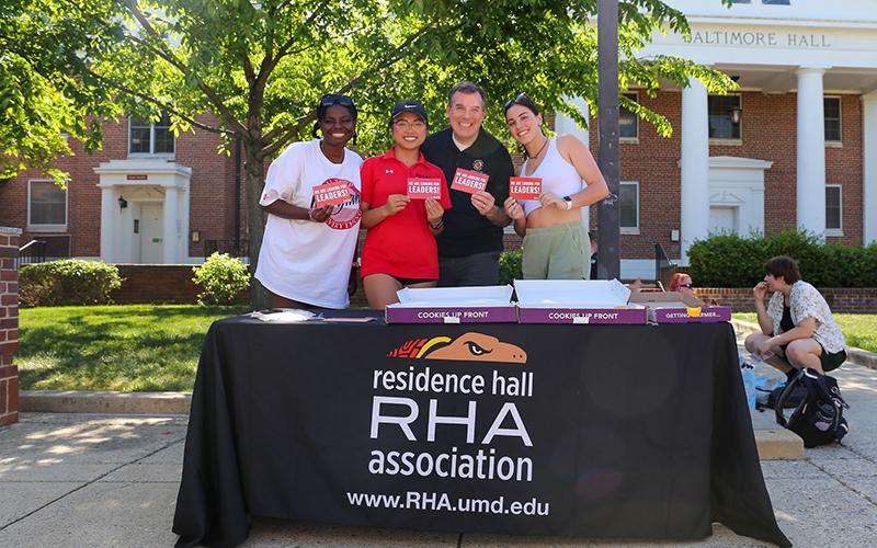 Four people smiling at a Residence Hall Association tabling event on Washington Quad.