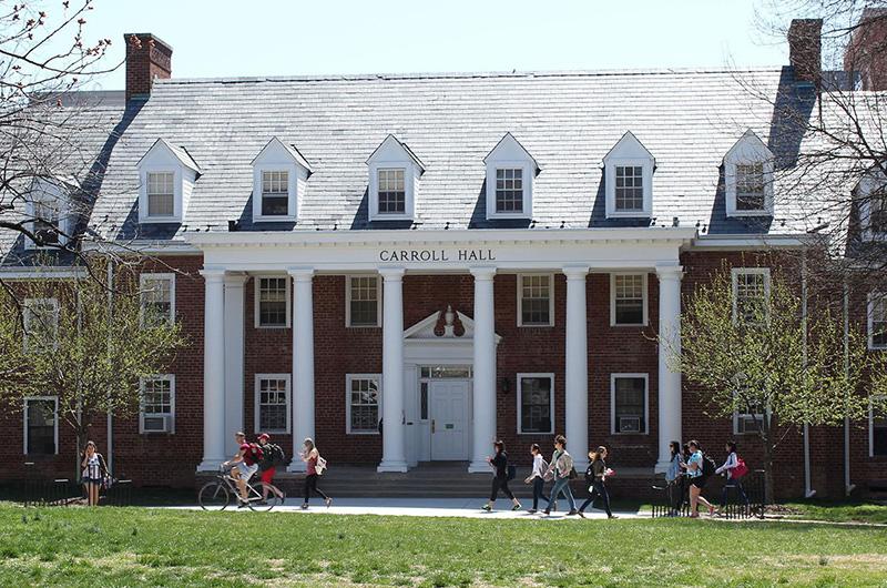 Exterior of Carroll Hall, a brick residence hall featuring white columns and multiple roof dormers.
