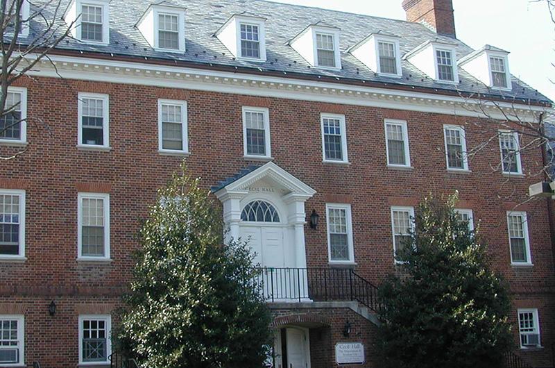Exterior of Cecil Hall, a brick residence hall with a white arched entryway and roof dormers.