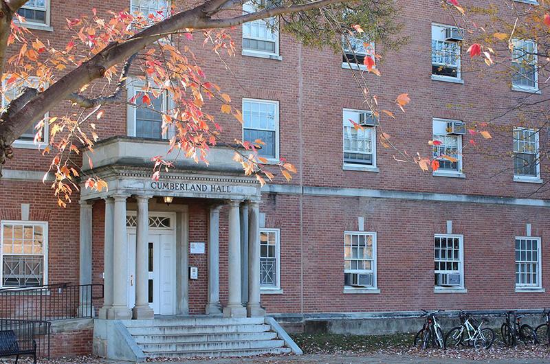 Exterior of brick Cumberland Hall with white pillars and autumn trees in the foreground.