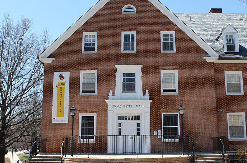 Exterior of Dorchester Hall, a brick building with a white entrance and a "Global Communities" banner.