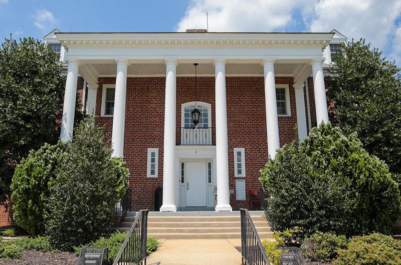 Brick House 3 with four large white pillars and a small balcony above the entrance.