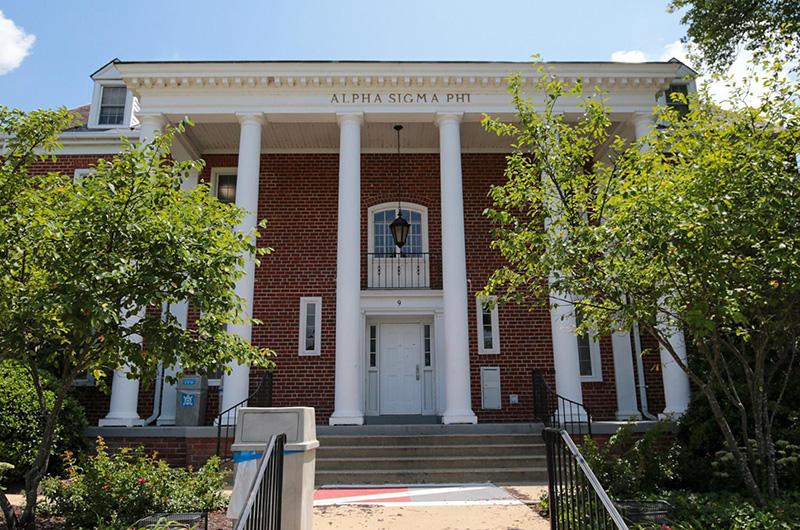 Exterior of brick Alpha Sigma Phi house with four white pillars and a small balcony.
