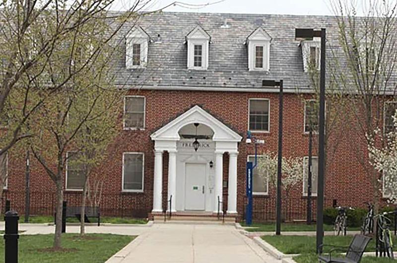 Exterior of Frederick Hall, a brick residence hall with a white pillared entrance and roof dormers.