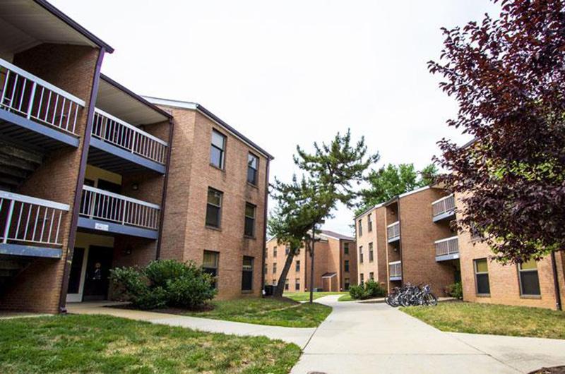 Exterior of brick Leonardtown Community buildings with balconies and paved walkways.