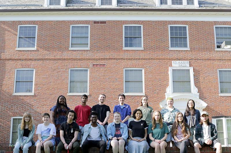 A group of students sitting on a brick ledge in front of St. Mary's Hall.