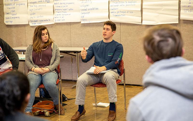Student speaking during a seated group dialogue session.