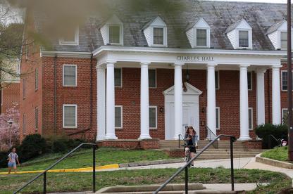 Exterior of Charles Hall, a brick residence hall with a white pillared porch and roof dormers.