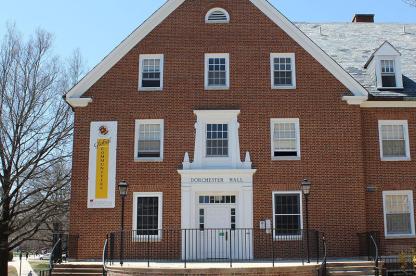 Exterior of Dorchester Hall, a brick building with a white entrance and a "Global Communities" banner.